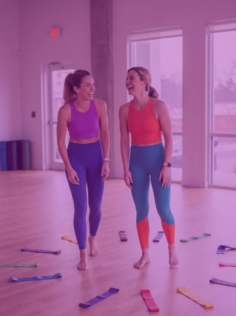 Due amiche che ridono in sala tra gli elastici colorati